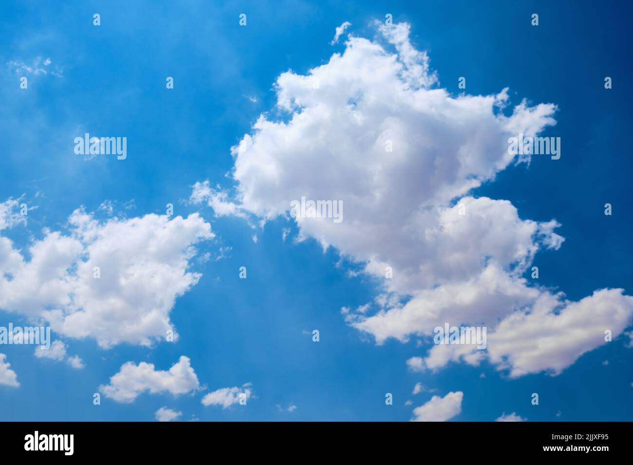 Cumulus clouds against bright blue sky Stock Photo