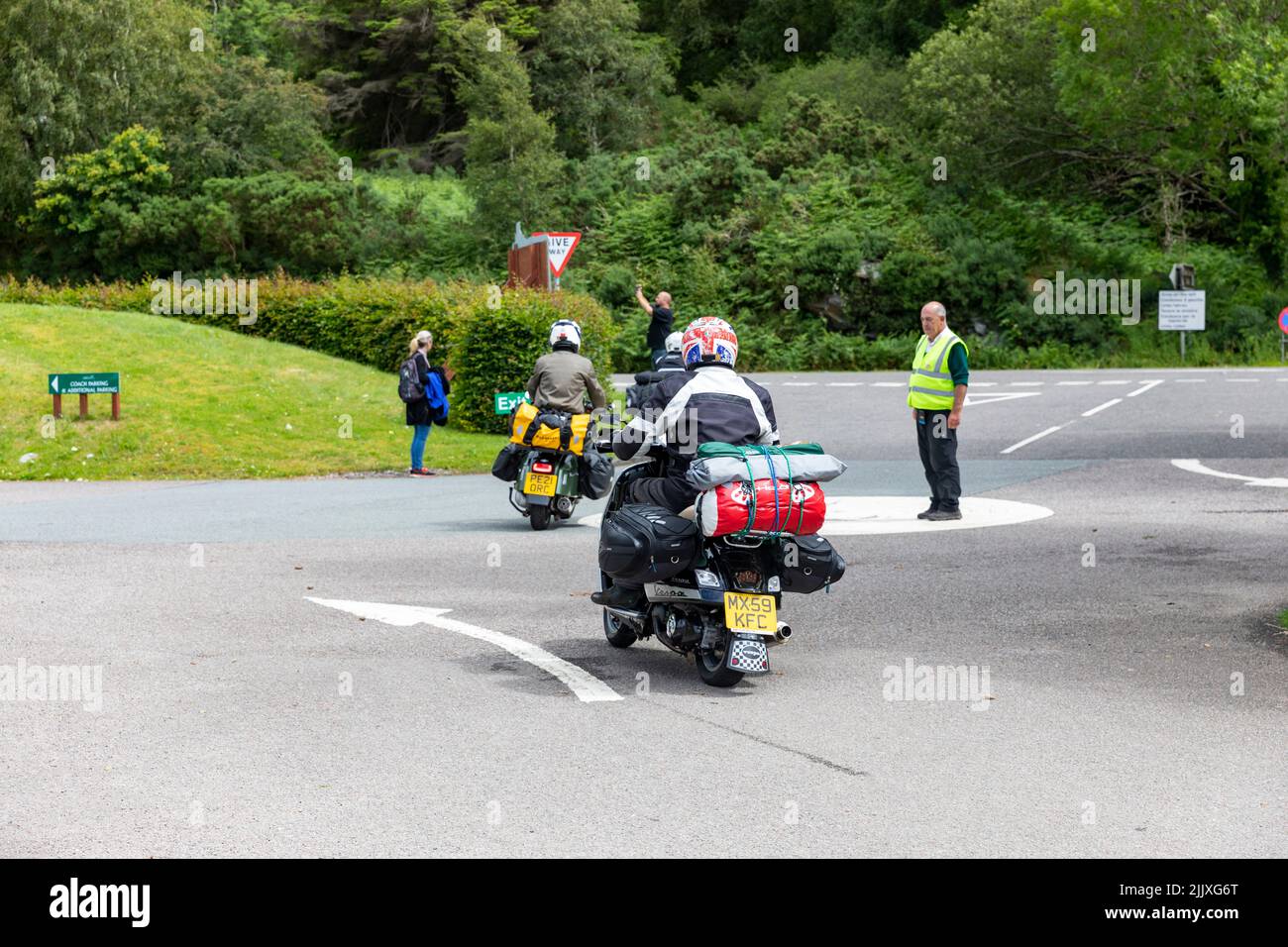 Scooter riders, with camping equipment on the scooter, tour Scotland on two wheels, leaving Glen Coe,Highlands,Scotland,UK Stock Photo