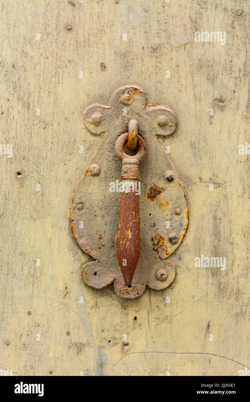 Rusty knocker centered on an old, yellowed wooden door, with copy space Stock Photo
