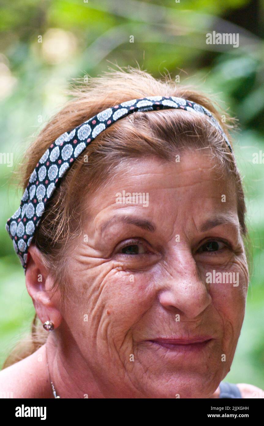 Head Portrait Photo Of a Woman i her Sixties with a wrinkled Face wearing headband Stock Photo