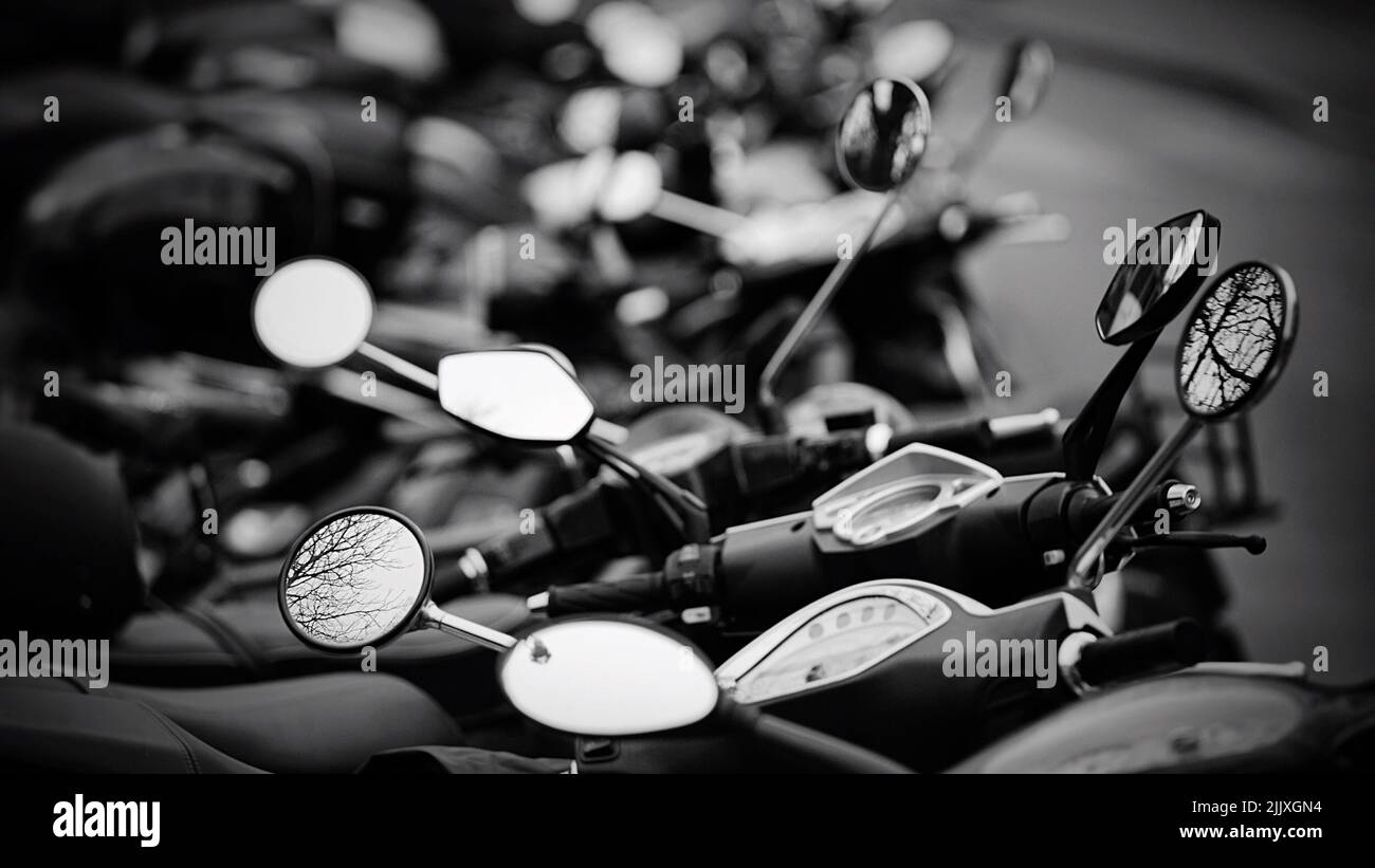 A selective focus grayscale shot of multiple motorbikes parked close to ...