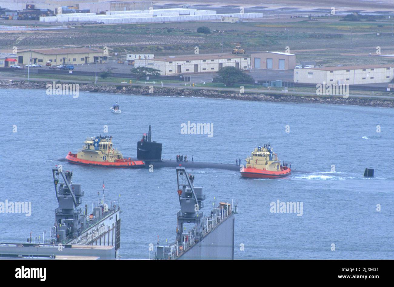 C-tractors guide a U S Navy submarine towards the dock at Naval Base Point Loma, San Diego, California Stock Photo