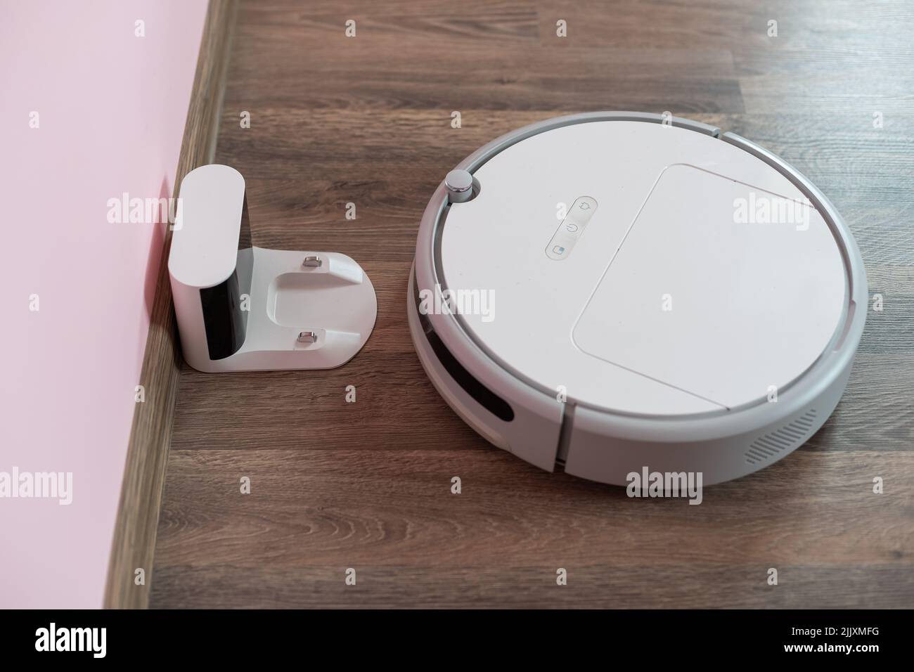 Robotic vacuum cleaner on laminate wood floor charging from base