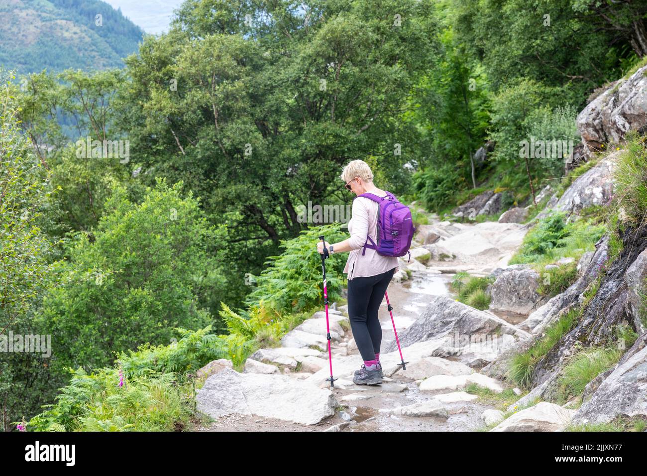 Ben Nevis Scotland, woman hiker fifties, with hiking poles hikes down from Ben Nevis mountain, along stone path,Scotland,UK, summer 2022, model releas Stock Photo