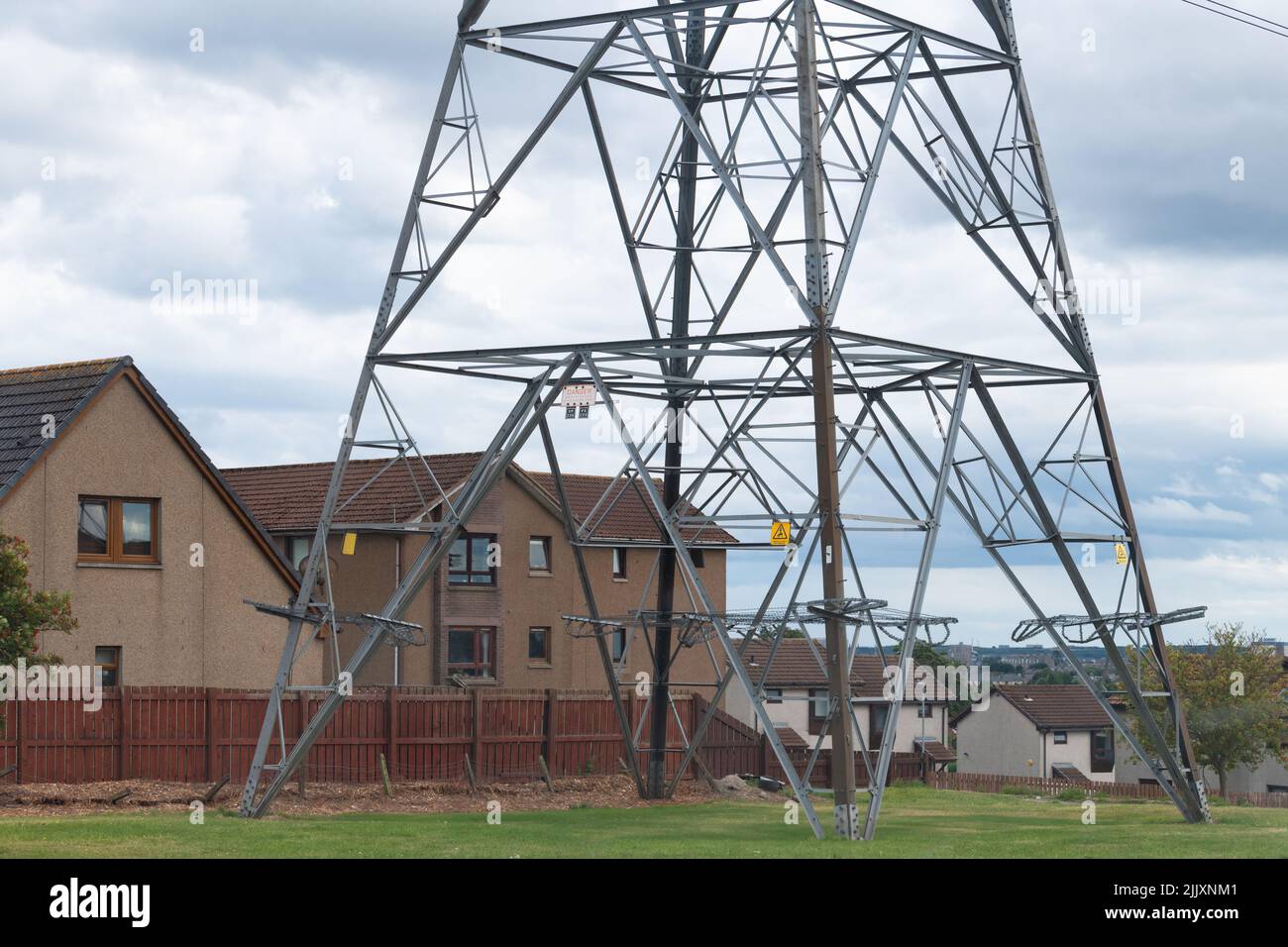 electricity pylon next to houses - Danestone, Aberdeen, Scotland, UK Stock Photo