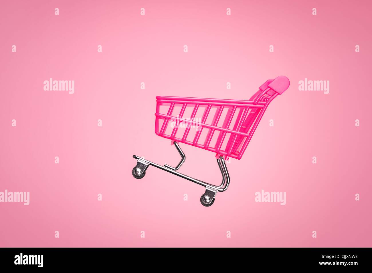 Pink shopping trolley supermarket concept. Empty trolley cart isolated pink background. Sale cart shop online marketplace. Toy pink concept sales Stock Photo