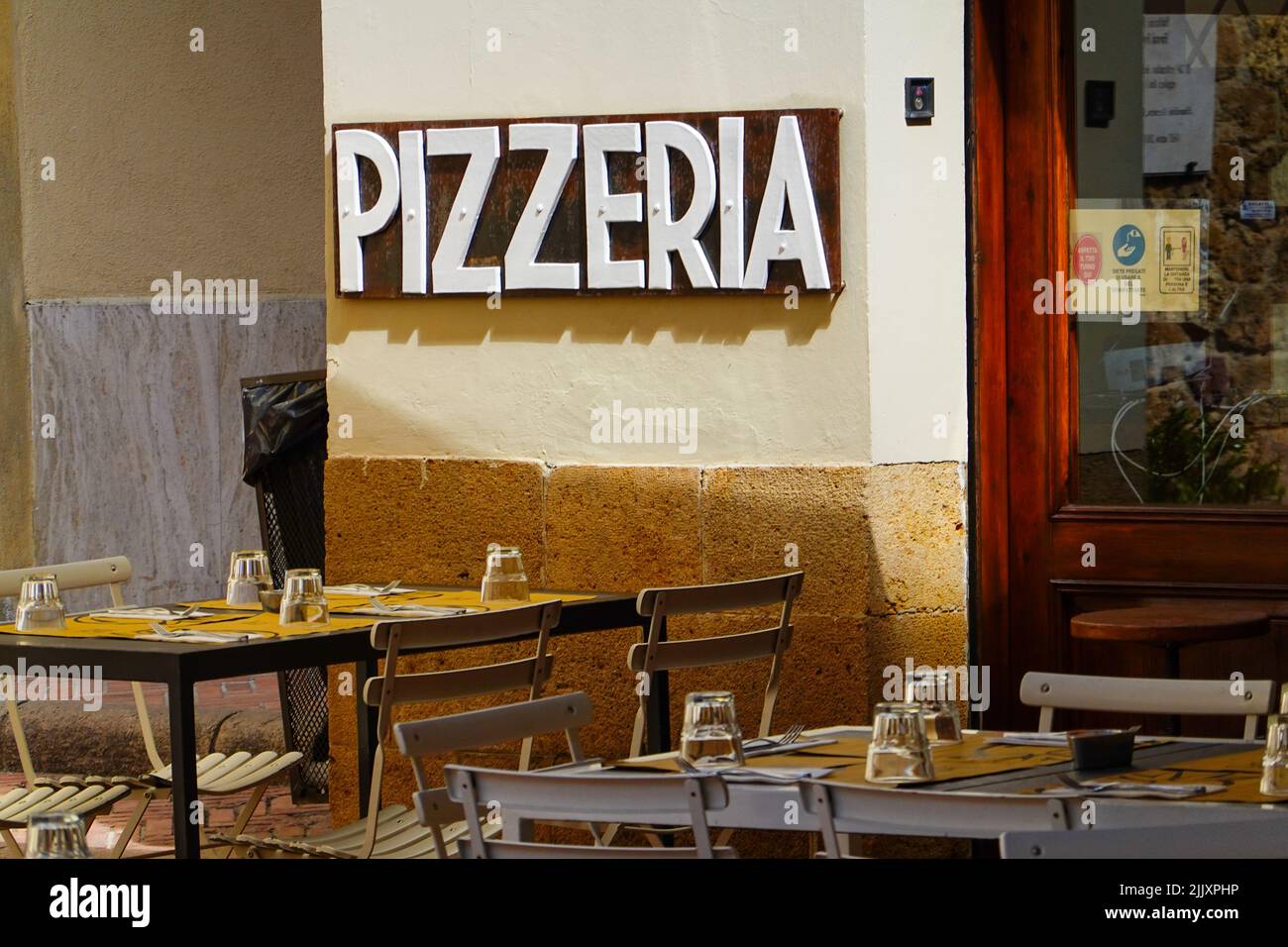 Empty outdoor tables set up for food service at the pizzeria in the town of Pienza, Val d’Orcia part of Tuscany, Italy. Stock Photo