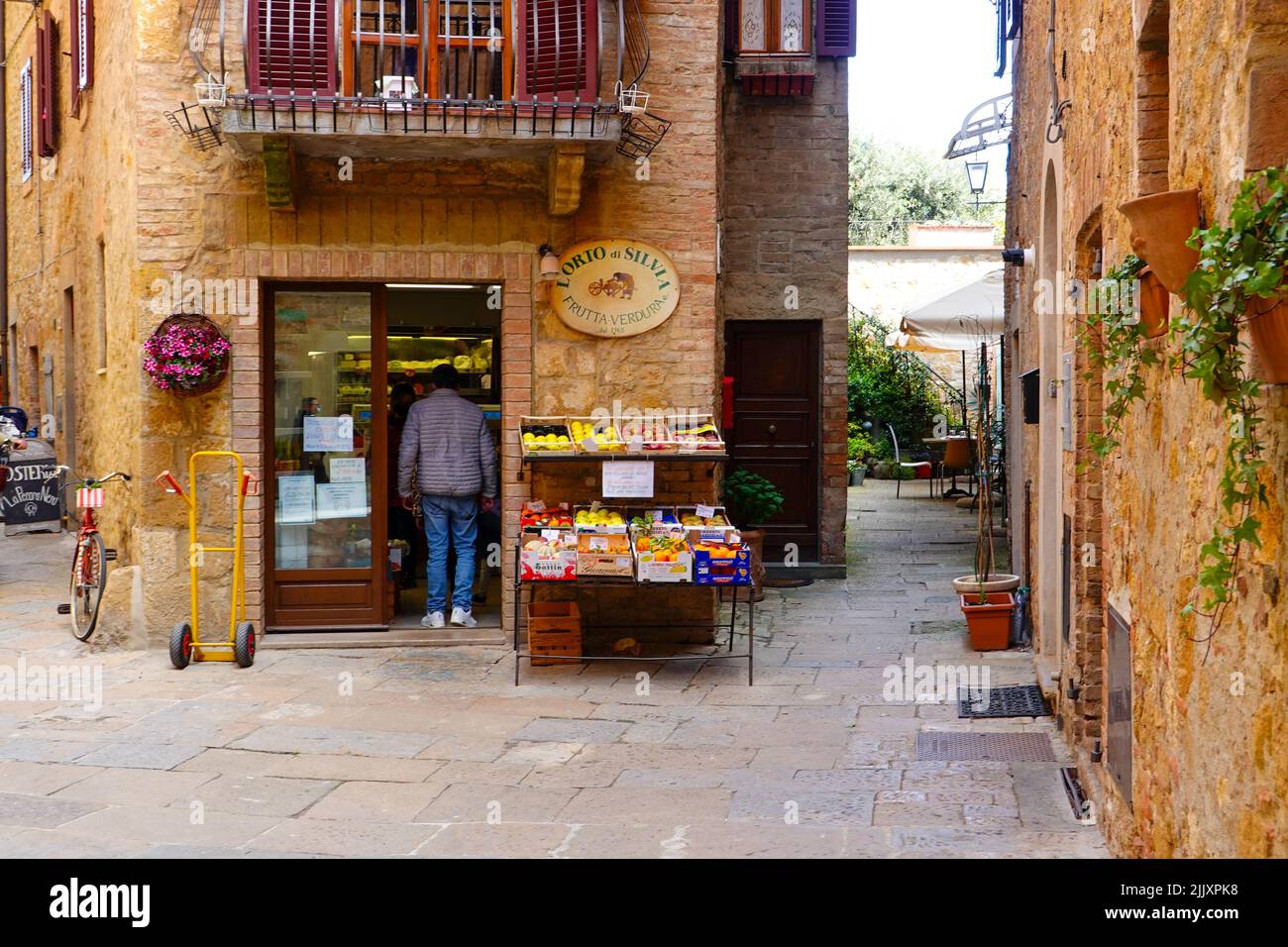 People entering the L’Orto di Silvia fruit and vegetable market located in the Val d’Orcia hill town of Pienza, Italy, in the heart of Tuscany. Stock Photo