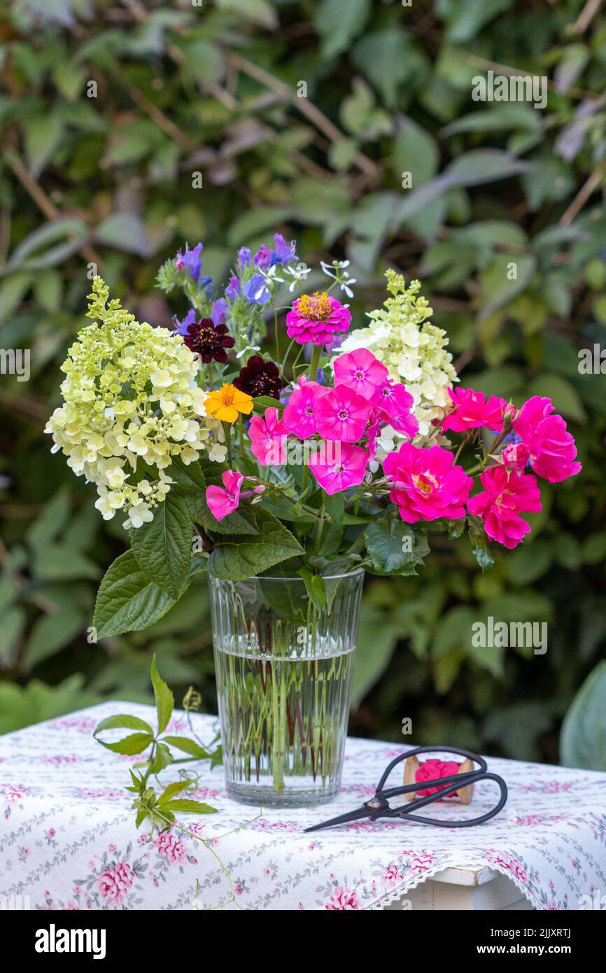 bouquet of phlox, roses and hydrangea flowers in glass vase Stock Photo