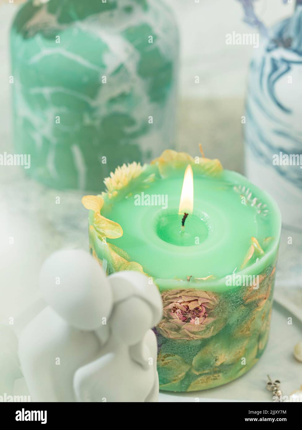 Handmade candles of a unique design, with different flowers, dry leaves on a light background. Candles made from organic wax, paraffin wax. Relaxation Stock Photo