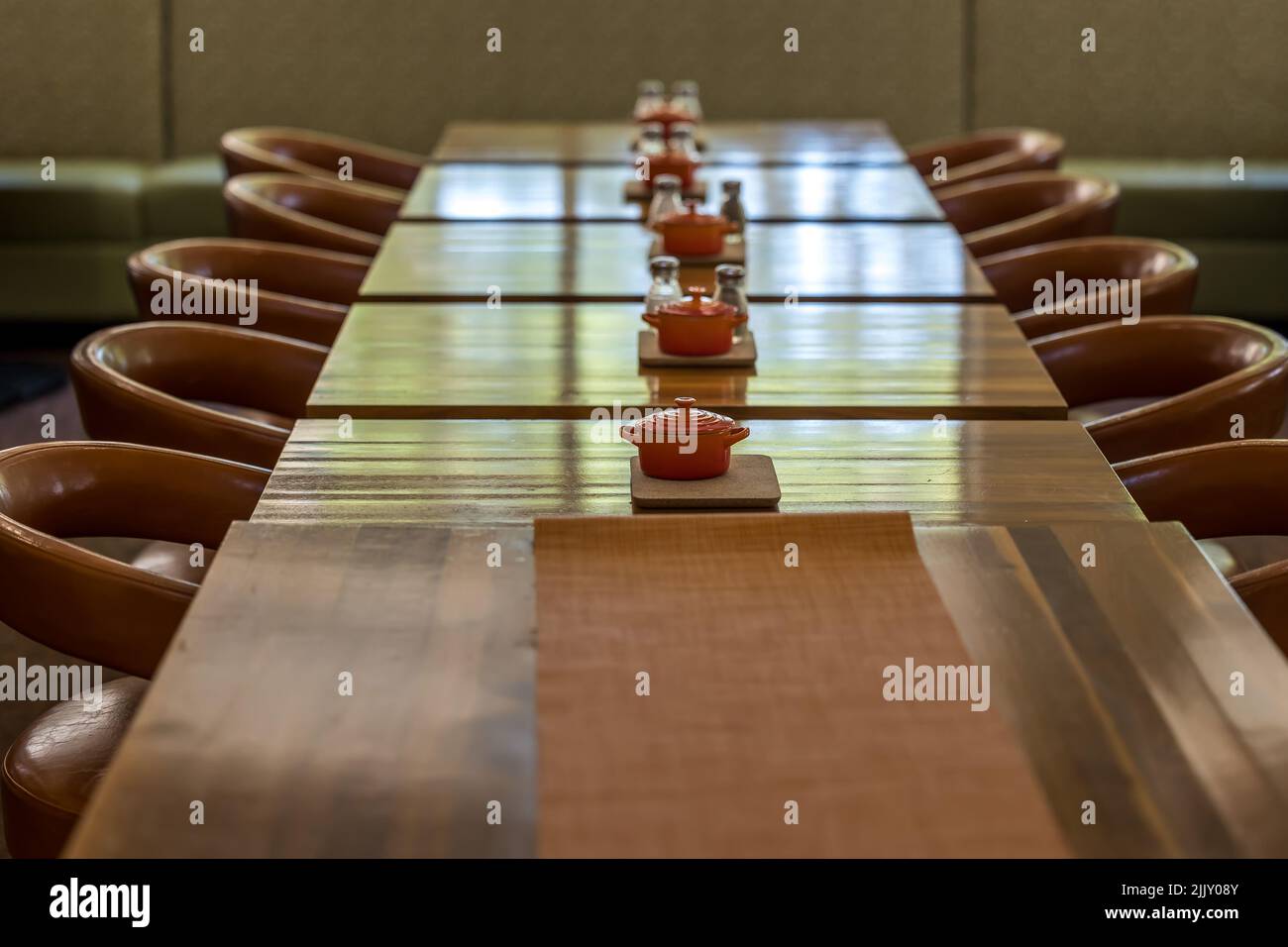 A long empty table with chairs and table condiment minature crocks for decoration Stock Photo