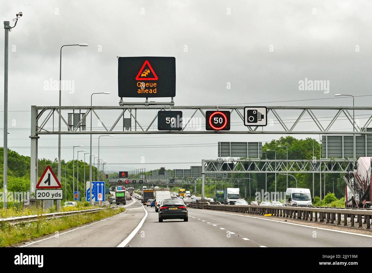 Bristol, England - May 2022: Traffic approaching a queue on the M4 motorway near Bristol, with speed limit warning signs overhead. Stock Photo