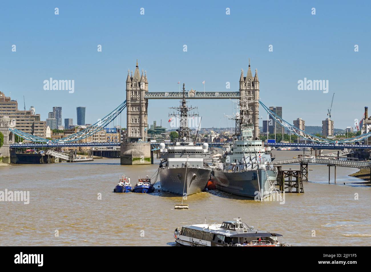 London, England - June 2022: HMS Belfast and a modern Royal Navy warship moored on the River Thames. In the background is Tower Bridge. Stock Photo