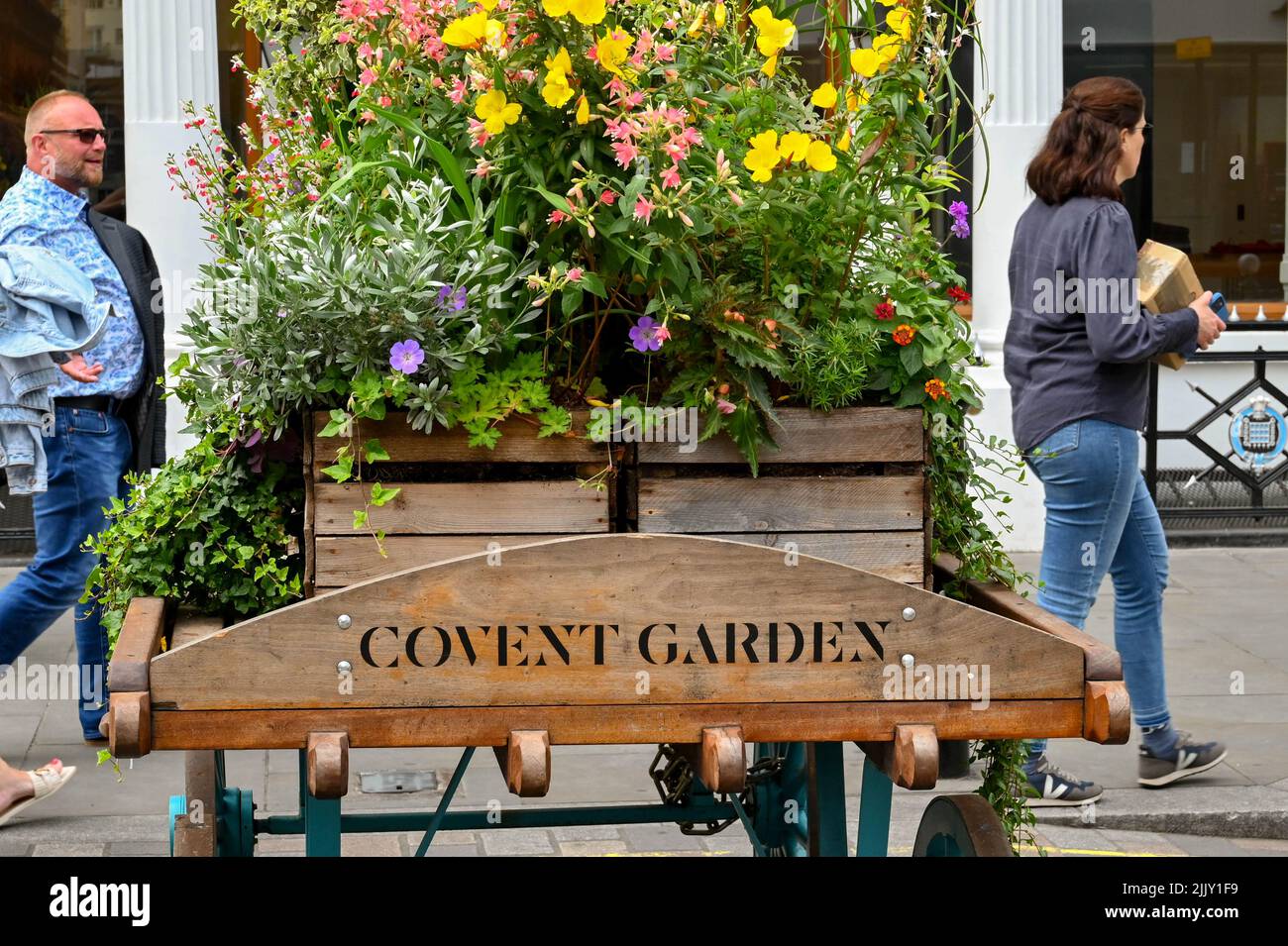 London, UK - June 2022: Sign carved into an old wooden cart with a flowerbed on top advertising the entrance to Covent Garden Stock Photo