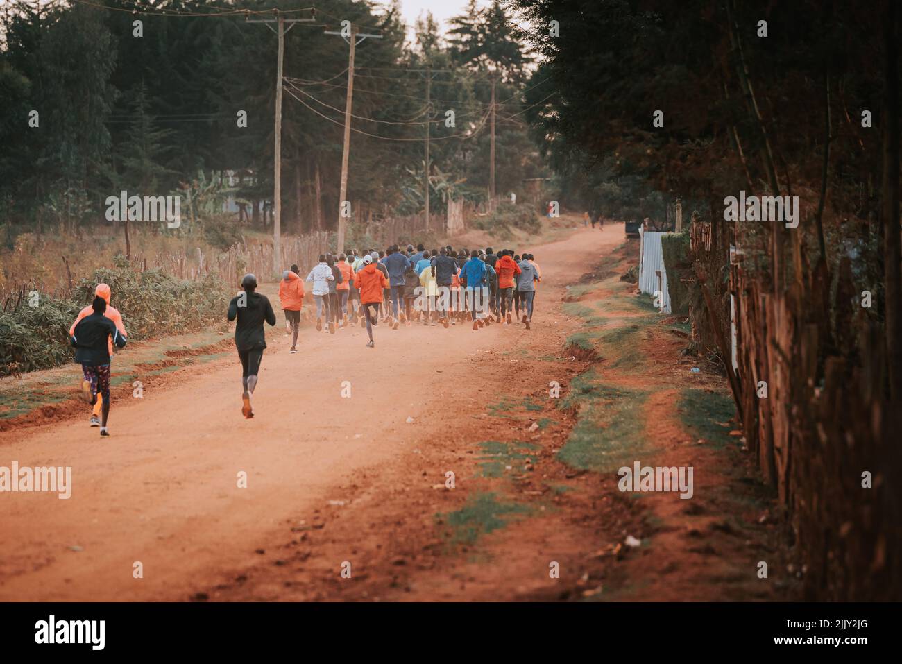 Group of runners on a morning mass training in Kenya. Africans running on red roads in iten city. Running preparation for marathon races Stock Photo