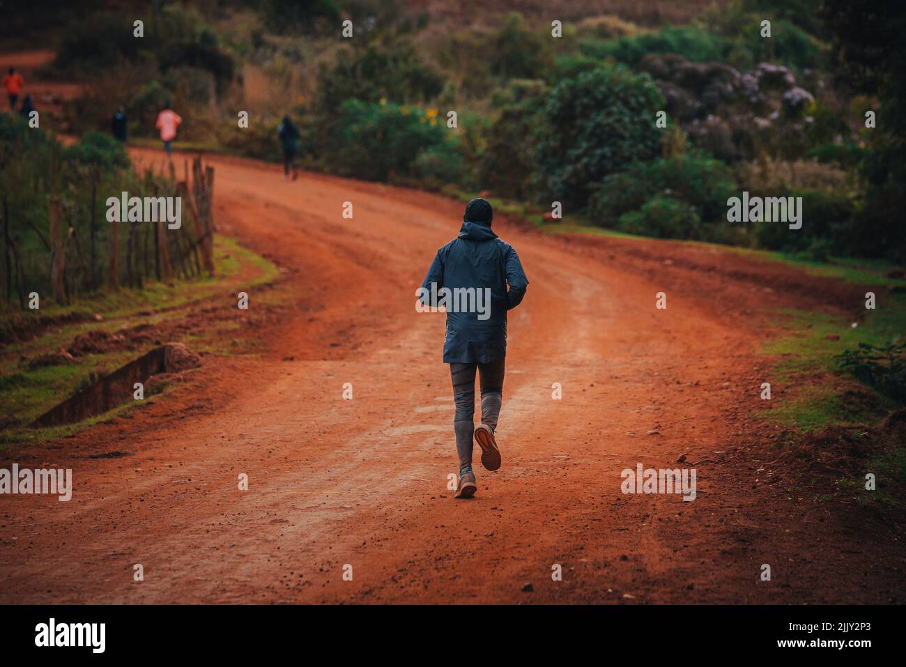 Morning run in Kenya. A woman trains on the road with red soils and prepares for a race. Training camp in the city of Iten in East Africa Stock Photo