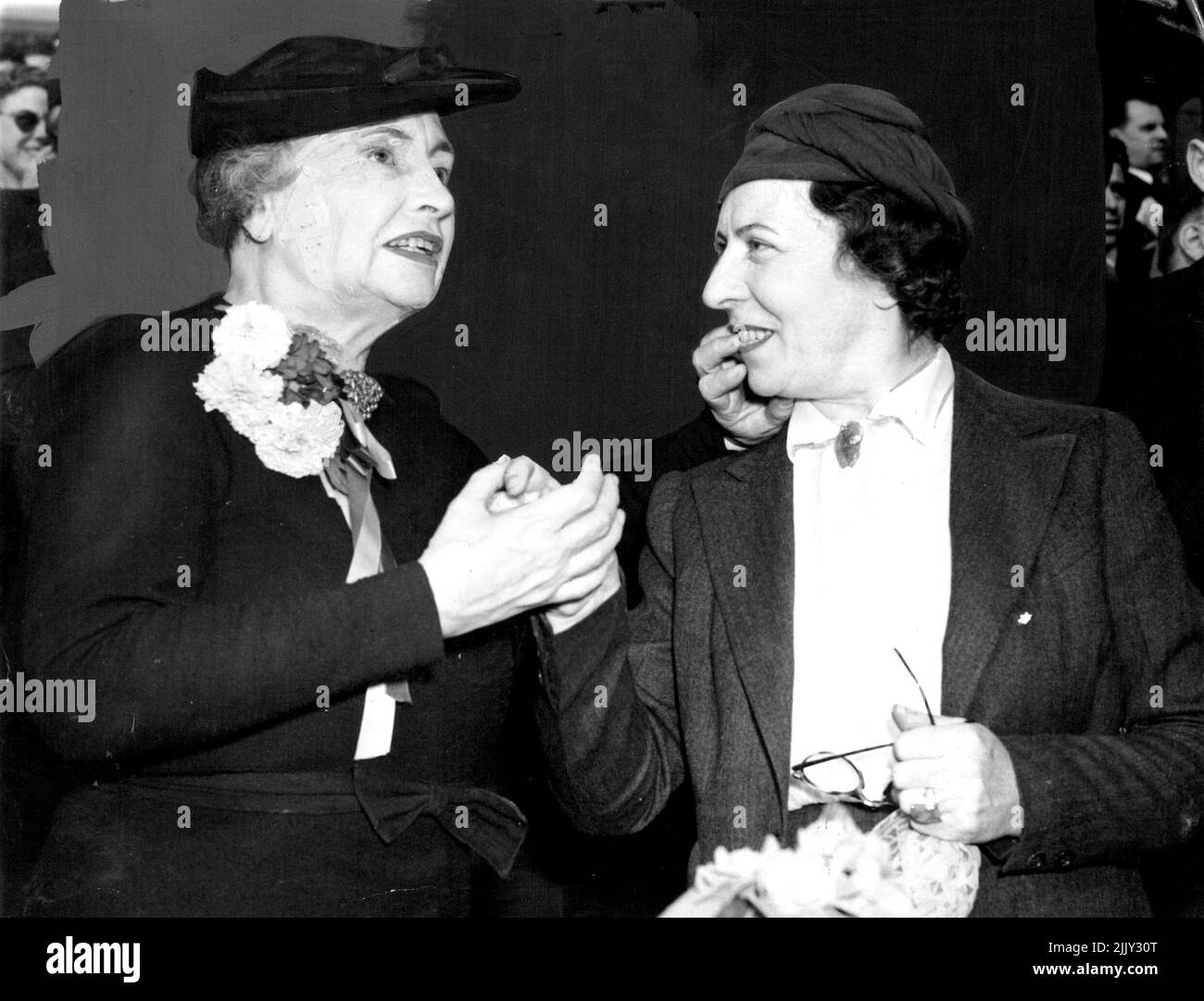 Helen Keller 'Sees' Football - Blind and deaf, Helen Keller, lecturer, and author, rooted like a regular fan Oct. 8, at a Minneapolis Gridiron as her companion, Miss Polly Thomson, 'Telegraphed a play-by-play account of Minnesota's 7-0 victory over Purdue, through their clashed hands. Here, Miss Keller, left, 'Hears' by touch the band musicas Miss Thomson taps out the notes and Whispers the words. September 10, 1938. (Photo by Associated Press Photo). Stock Photo