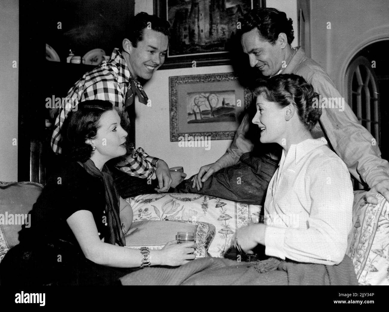 Lady Olivier, Mrs. Michael Redgrave, and standing, left to right: Mr. John Tullis and Mr. Peter Finch. Lady Olivier and party to square dancing at the Chelsea Town Hall. Before leaving for the dance they had a snack at the Oliviers' home. Before going on to a square-dance party, she relaxed in he Chelsea home over a drink with (L.to R.) actor John Tullis, Australian Peter Finch and the wife of film star Micheal Radgrave. January 8, 1953. (Photo by Daily Mail Contract Picture). Stock Photo