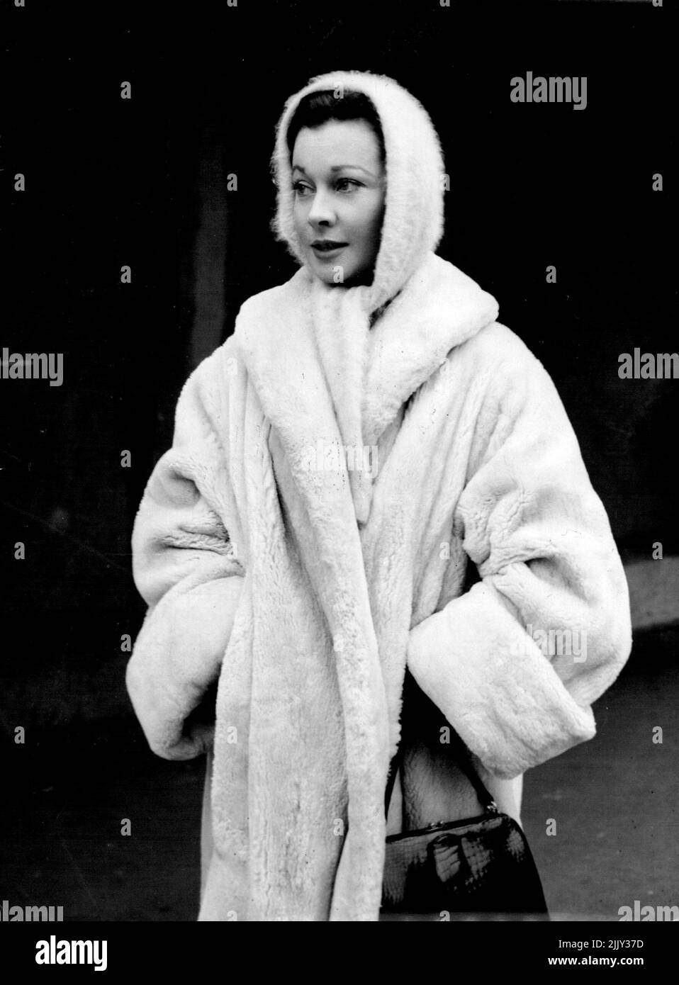 Arctic Britain brings appropriate dress by film star Vivien Leigh, who ***** into a cosy-looking white lamb coat and woolen, hand-hugging cap and scarf on the way to luncheon at Shepperton Studios, Middlesex, where she was just started work - on the London Films presentation 'The Deep Blue Sea.' Appearing in the film with her are Kenneth here, Eric Portman and Emlyn Williams. January 18, 1955. (Photo by Reuterphoto). Stock Photo