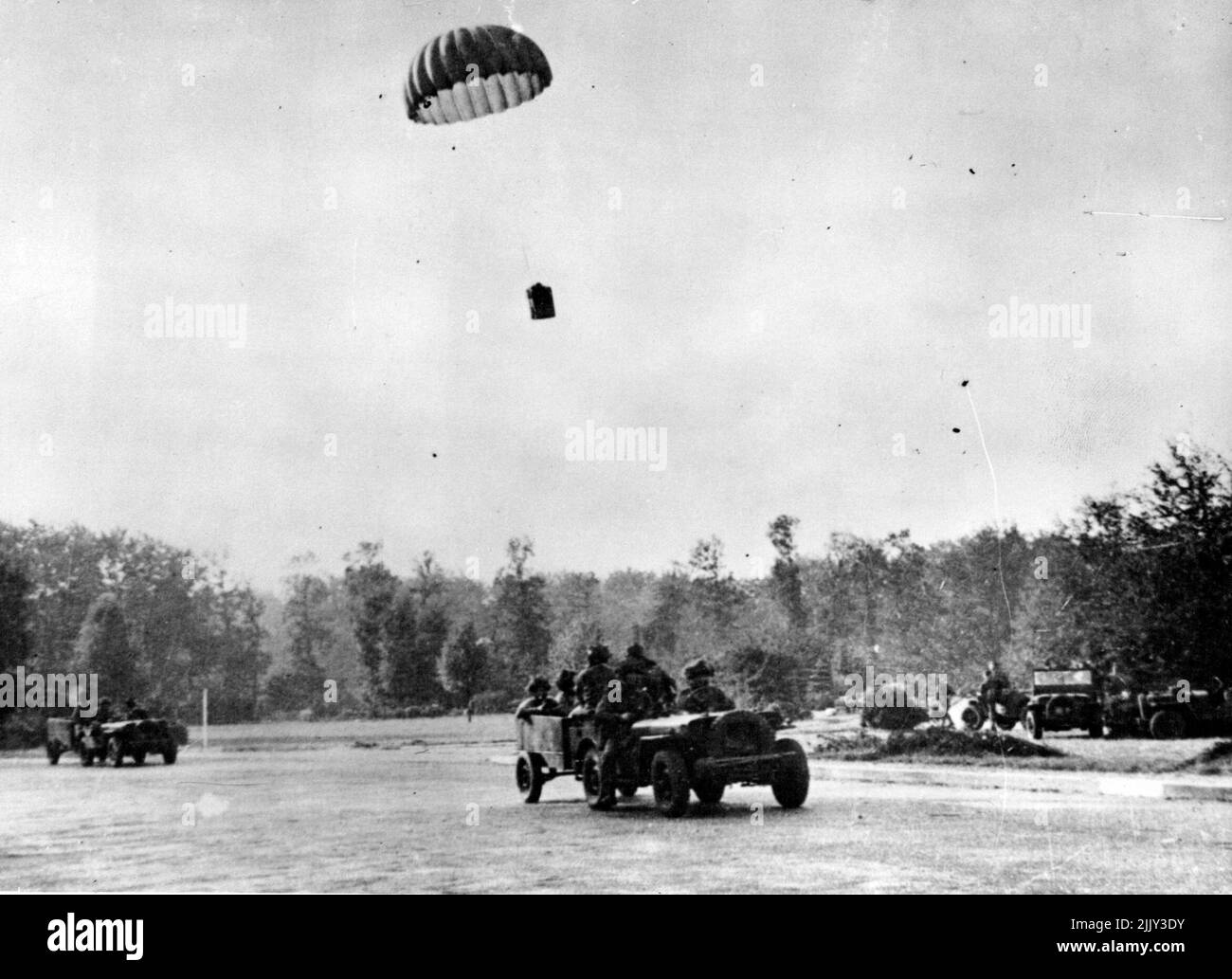 ture Of British Airbourne Forces In Holland -- A supply basket dropping on a roadway to be collected by airborne forces with jeeps. When the 1st., Allied the 1st. Allied Airbourne army was dropped in Holland, photographers of the Army Film and Photographic Unit were with them. This is one of the first photographs received back from them. One of the photographers writes in a letter dated Sep. 20th., 'This is the fourth day if fighting an camera work is almost of the question. All day we have been under shell, morter and machine gunfire. December 04, 1944. (Photo by British Official Photograph). Stock Photo
