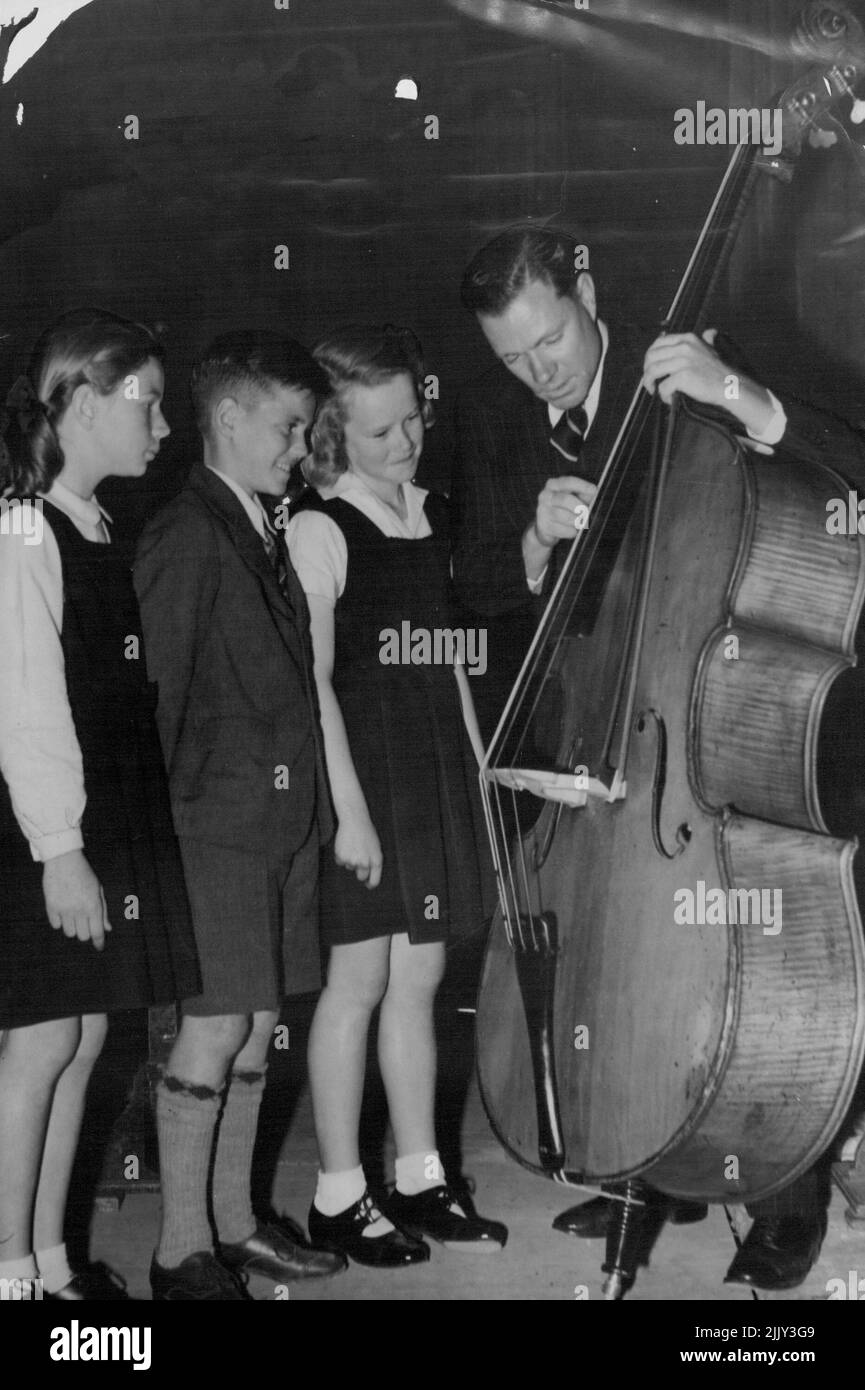 L. To R. Janet Skinner, Barrie Turner, Judith Mackay, Bill Key. Bill Key of the Sydney Symphony Orchestra explaining the double bass to some of the children of Clovelly School who brought in for the making of the film at Cinesound studios. November 28, 1946. (Photo by Molly Luke/Fairfax Media). Stock Photo