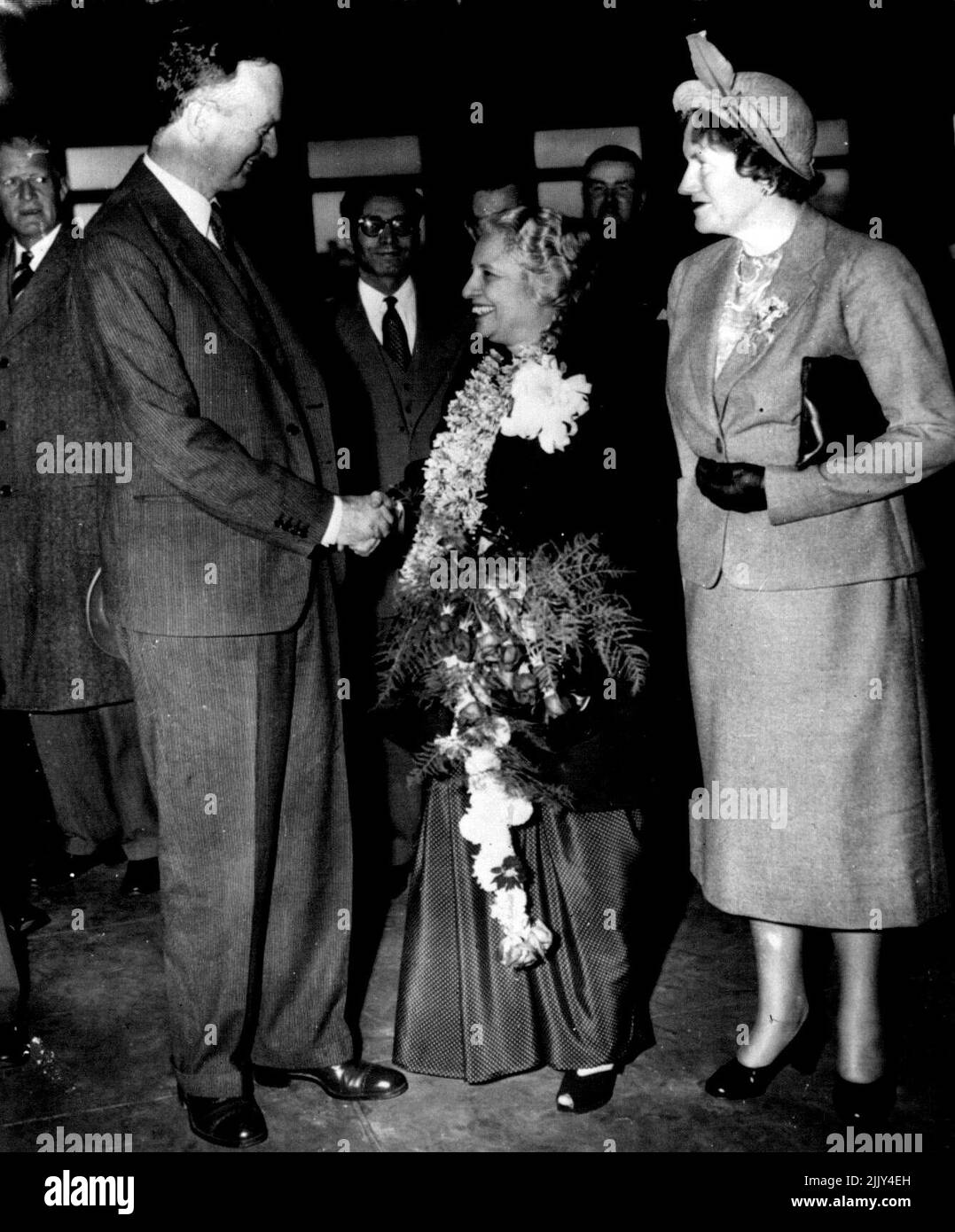 Goodbye To Madame Pandit - Madame Vijava Lakshmi Pandit, India's retiring ambassador, wears and carries farewell flower gifts as she receives a goodbye and a handshake from Sir Oliver Franks, British ambassador, at Union station this evening. Mrs. Franks (right) is with them, John Simmons (left background, state department protocol chief, represented the U.S. as Mme. Pandit left for New York on her way home. She will become a candidate for parliament in India's first constitutional election. November 15, 1951. (Photo by AP Wirephoto). Stock Photo