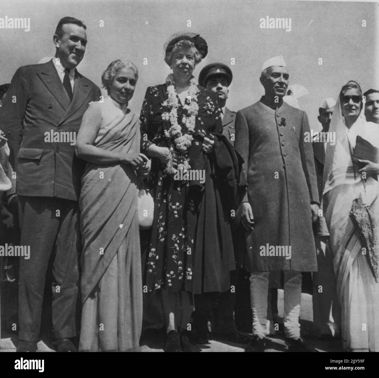 Indian Welcome For Mrs. FDR - A welcoming garland of blossoms adrons the neck of Mrs. Elanor Roosevelt as she is welcomed to New Delhi by members of India's first family last week. In group at the capital city's airport are (left to right) U.S. Ambassador to India Chester Bowles; Madame Pandit, former Indian ambassador to U.S.; Mrs. Roosevelt; Premier Jawaharlal Nehru; and Rajkumari Amrit Kaur the Premier. Mrs. Roosevelt, who previously had visited Pakistan, denied that the visit had any political significance. March 2, 1952. (Photo by AP Wirephoto). Stock Photo