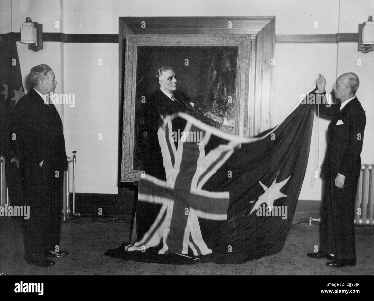The U.S. Charge d'Affairs, Mr. Orsen Nielsen, unveils a portrait of the late Franklin Roosevelt at Parliament House, Canberra, in the presence of the Prime Minister, the Rt. Hon. J.B. Chifley. The portrait was painted by Franck Salisbury, R.I., and is a replica of one hanging at Hyde Park, New York State. It will from part of the Roosevelt Memorial library at Canberra. November 11, 1948. Stock Photo