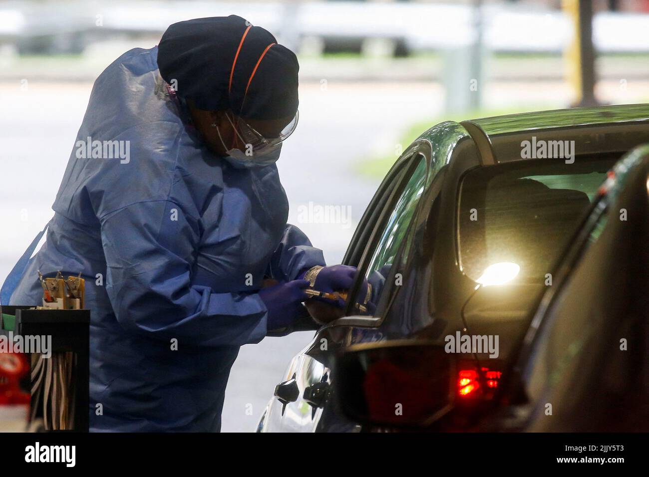 A staff member of the Westchester Medical Center applies a monkeypox vaccine to a person in a drive-through monkeypox vaccination point at the Westchester Medical Center in Valhalla, New York, U.S., July 28, 2022. REUTERS/Eduardo Munoz Stock Photo