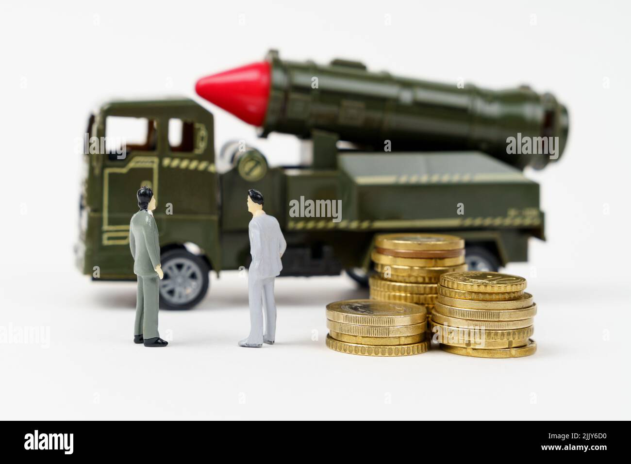 The concept of the military budget. On a white surface are figurines of people, coins and a toy military vehicle. Stock Photo