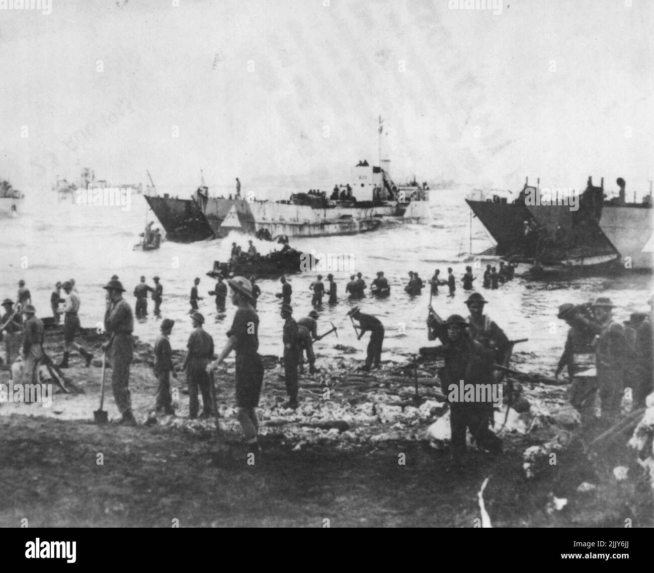 Unloading Stores At Sicily -- Allied soldiers stand waist deep in water as they pass along stores from landing craft during the first day of the Sicilian invasion, July 10. In the foreground. This photo was taken just after dawn by an official British photograph. July 25, 1943. (Photo by Associated Press Photo). Stock Photo