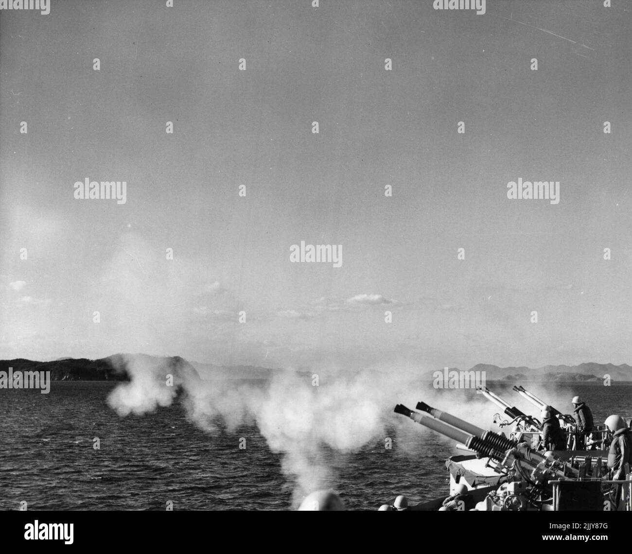 ***** above on the heavy cruiser USS Los Angeles ***** in readiness towards ***** gun ***** Monsan. Hanging in the air the smoke from the five and sight inch guns that pounded Wonsan for more than eight continuous hours the previous day. October 23, 1951. (Photo by Official U.S. Navy Photograph) Stock Photo