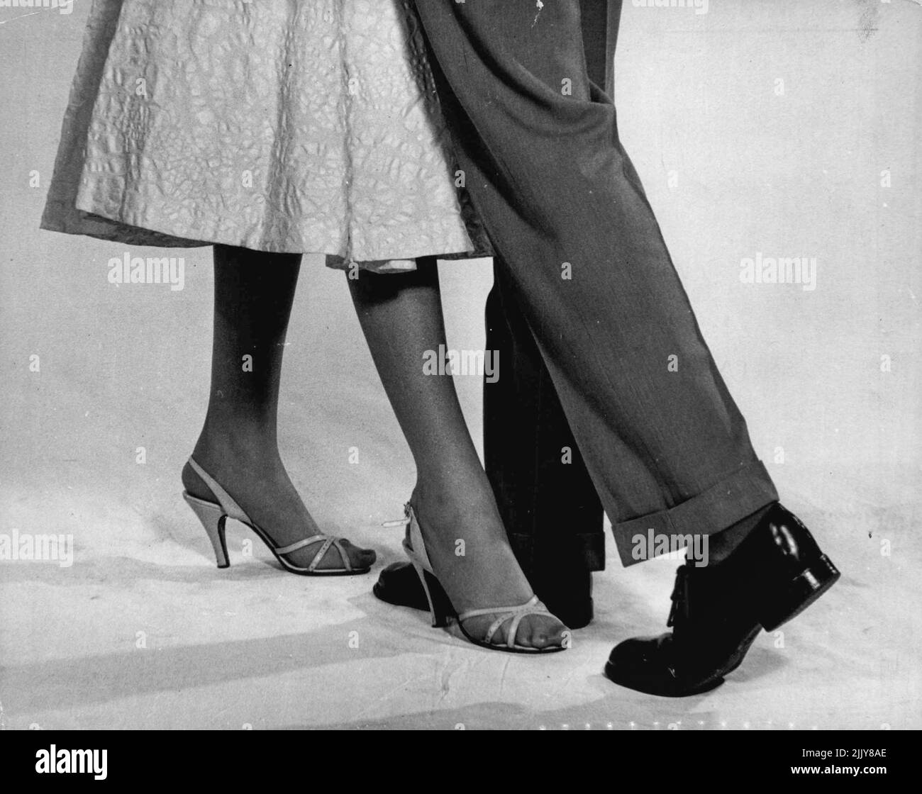 First Step: The man steps forward with his right foot, turning right. The girl brings left foot back, turning to the right. March 14, 1955. Stock Photo