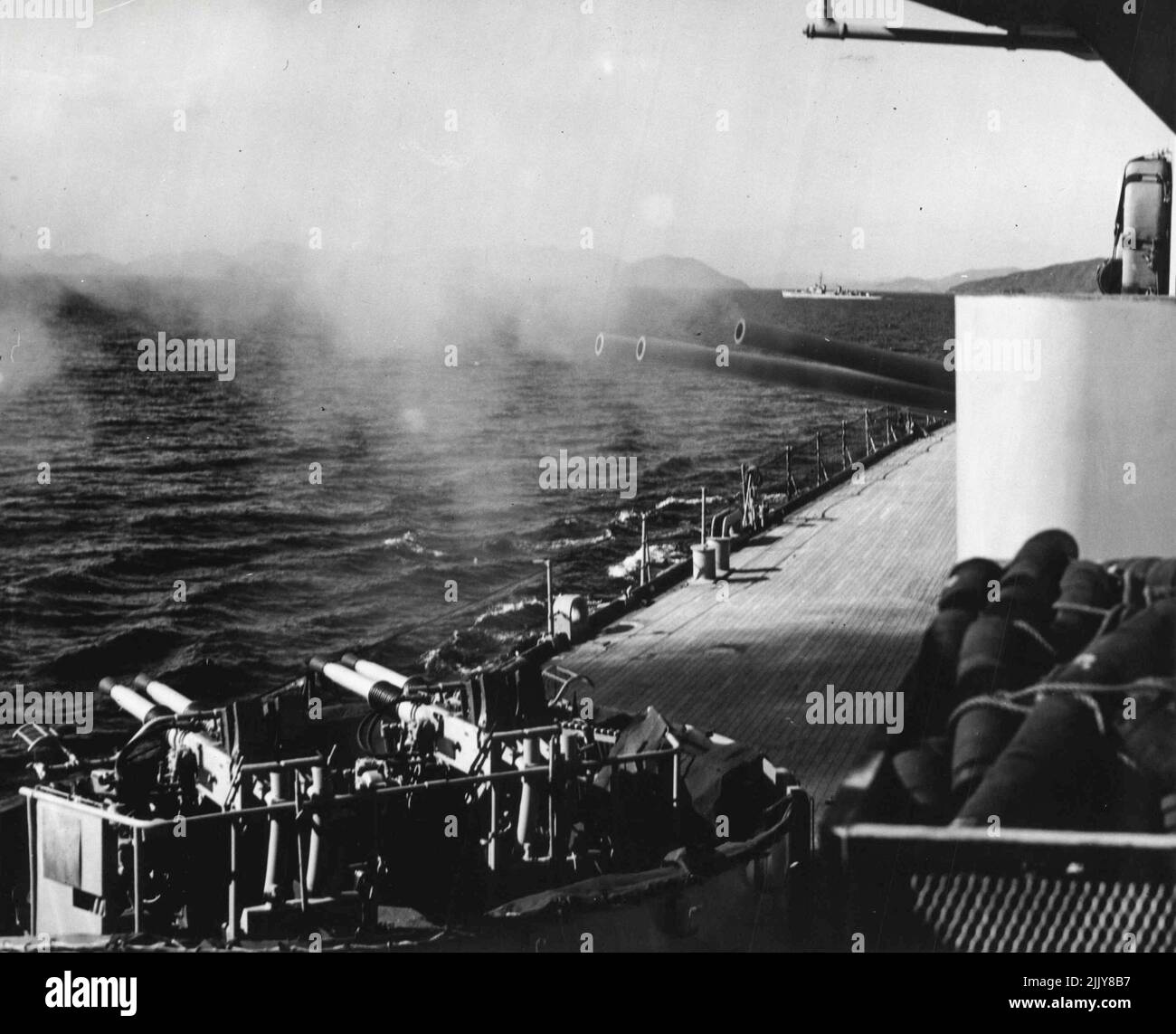 The Big eight inch guns of the heavy cruiser Los Angeles are shown as they boom a fiery message across Wonsan Harbor during a constant day-long bombardment of the besieged coastal port. The Los Angeles brought her eight and five inch guns to bear on enemy supply routes and military installations in and around Wonsan throughout the day. In the background is the destroyer USS Lyman K. Swenson, which screened the Los Angeles during Wonsan Operation. October 23, 1951. (Photo by Official U.S. Navy Photograph). Stock Photo
