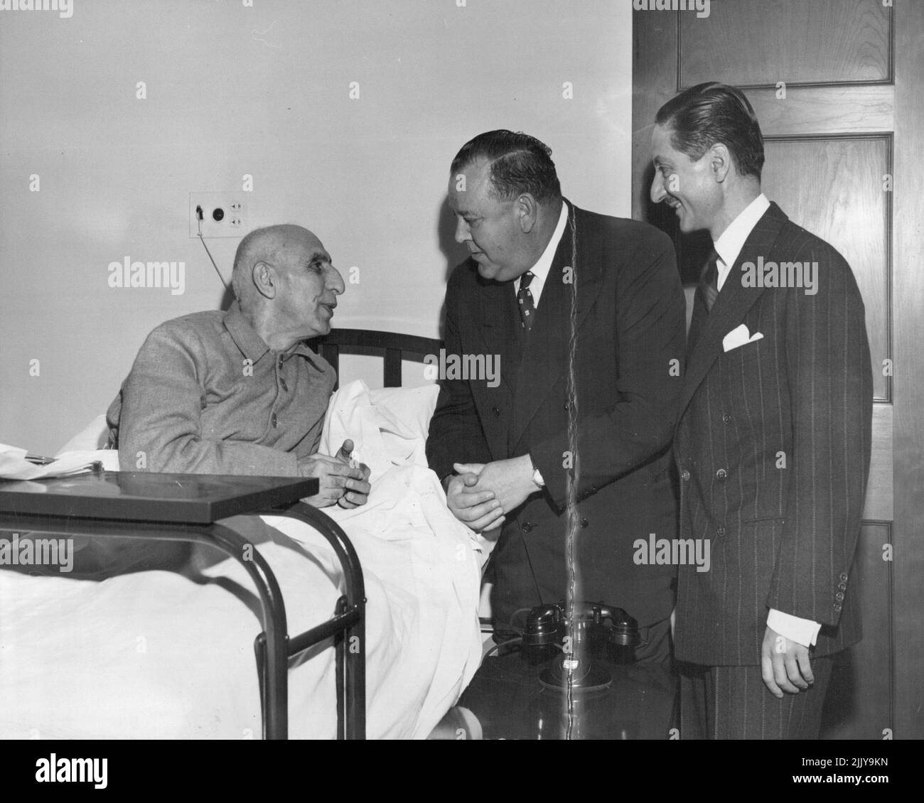 Trygve Lie Visits Dr. Mossadegh -- United Nations Secretary-General Trygve Lie (center) pays a visit in New York Hospital to Dr. Mohammed Mosssadegh, Prime Minister of Iran. At right, Ambassador Nasrollah Entezam, of Iran, President of the fifth session of the General Assembly. Dr. Mossadegh is presently in New York to attend the Security Council meetings on the Iranian oil dispute. October 12, 1951. (Photo by UNations). Stock Photo