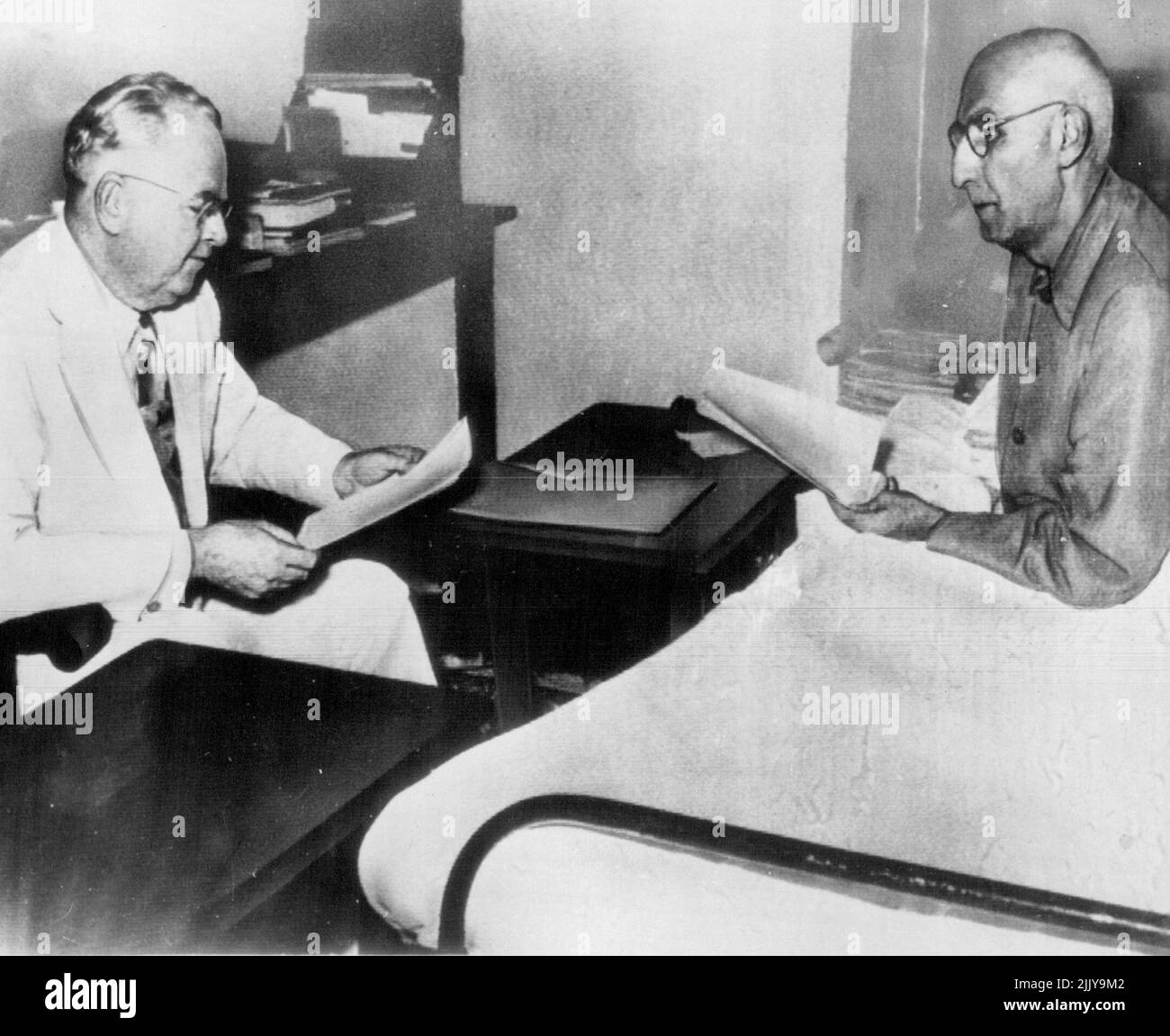 Iranian Premier Gets Truman Offer - Iranian Premier Mohammed Mossadegh (right), confined to his bed and wearing pajamas, talks with Henry F. Grady, U.S. ambassador to Iran, in Tehran yesterday after receiving from Grady President Truman's appeal for settlement of the Iranian oil crisis. Truman offered to send his personal representative, Averell Harriman, to seek a settlement in the crisis which developed with nationalization by Iran of the British-owned Anglo-Iranian Co. July 10, 1951. (Photo by AP Wirephoto). Stock Photo