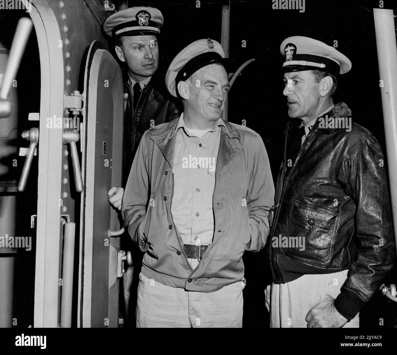 Bosun Larrabee (Millard Mitchell), centre, mistakes Harkness for a navy 'regular'; commiserates with him for landing on a 'teakettle' manned by green ox-civilians. Larrabee is the only man aboard with sea experience and even the first officer, Et.J.G. Bill Barron (Eddie Albert), left, is fresh out of training school. October 20, 1953. Stock Photo