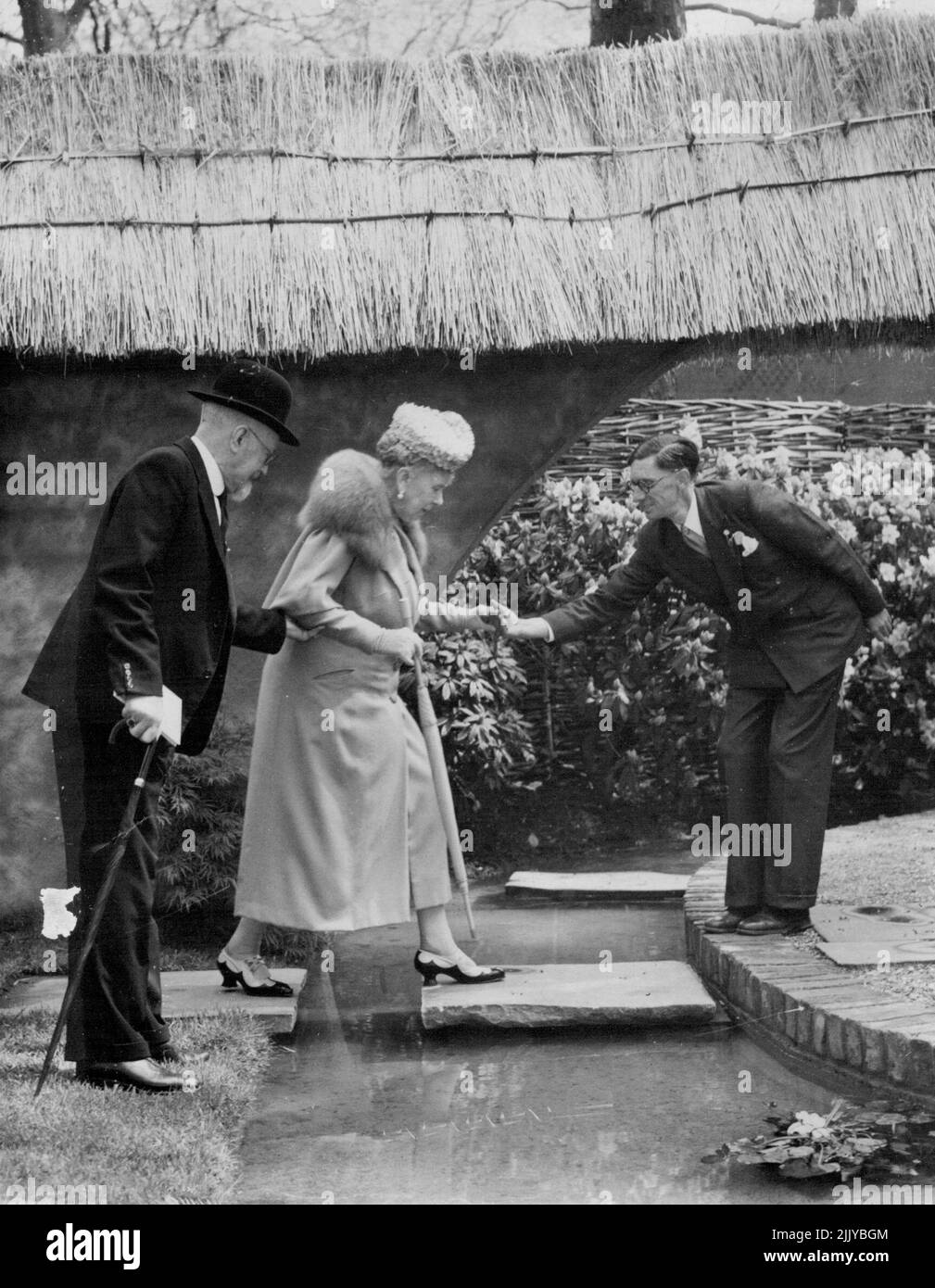 Queen Mary On The Stepping Stones -- Queen Mary, who will be 83 next Friday, crossing the stepping stones in the thatched walled garden when she toured the Chelsea Flower Show at the Royal Hospital, Chelsea, London today (Tuesday). Today was private view day; the show opens to the public tomorrow. May 23, 1950. (Photo by Reuterphoto). Stock Photo