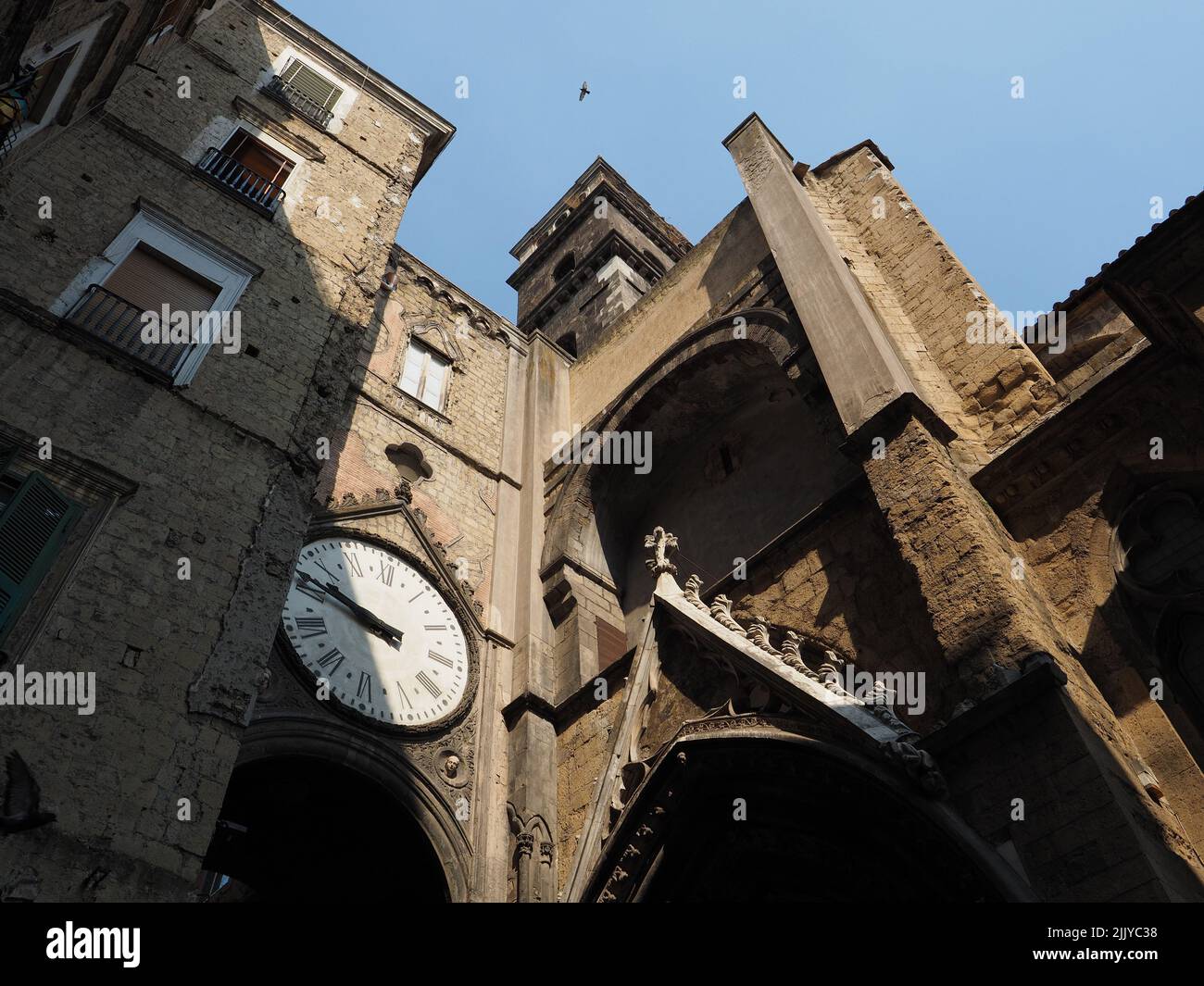 Church in Naples with little tower and clock in a bridge across the street. Napoli, Campania, Italy Stock Photo
