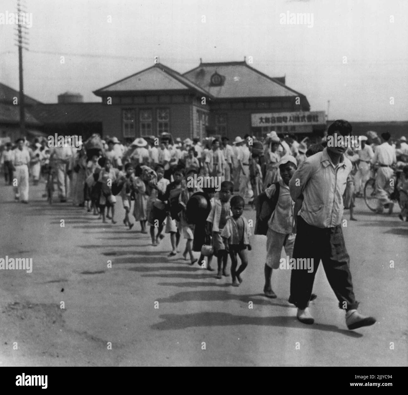Flee Advancing Red Army -- Carrying only a handful of their possessions, --and the little fellow has less than that--these South Koreans arrive in Taegu, Korea after fleeing from Taejon, 80 miles to north. Railroad station is in rear. July 19, 1950. (Photo by AP Wirephoto). Stock Photo