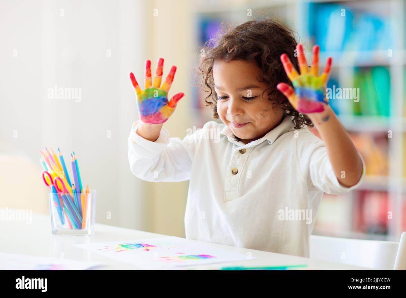 Child drawing rainbow. Paint on hands. Remote learning and online school art homework from home. Arts and crafts for kids. Stock Photo