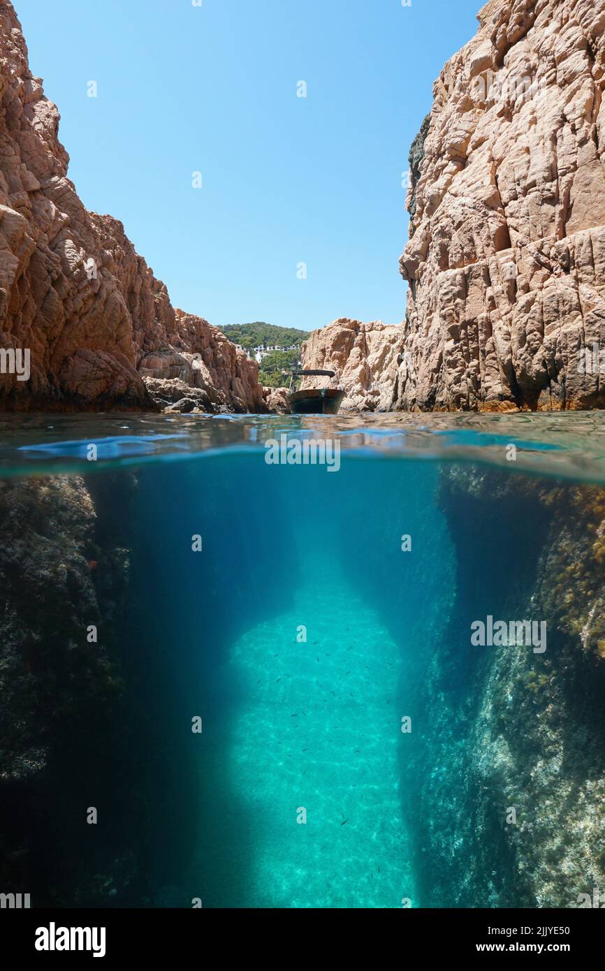Rocky coast with a boat in a narrow passage, split view over and under water surface, Mediterranean sea, Spain, Costa Brava, Catalonia Stock Photo