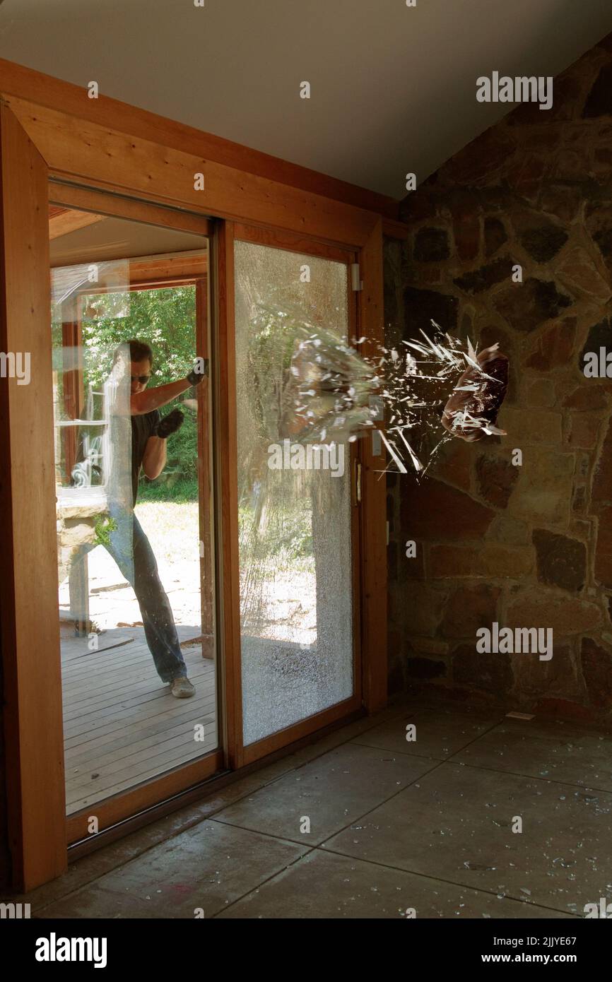 Rock being thrown through sliding glass door, Home Invasion, Smashed and shattered windows in a residential home Stock Photo