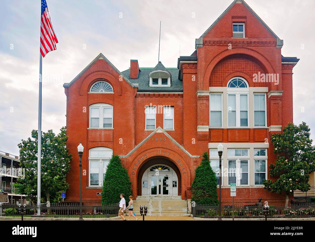 People walk in front of Oxford City Hall, May 31, 2015, in Oxford, Mississippi. Oxford City Hall was built in 1885 in the Romanesque Revival style. Stock Photo