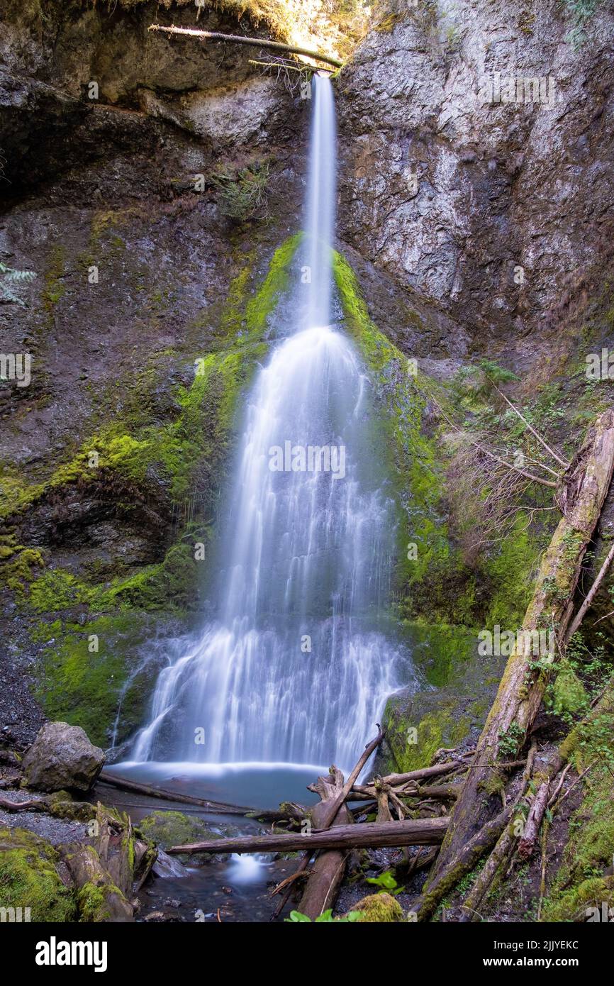 A vertical shot of a small waterfall on a rocky mountain during daytime ...
