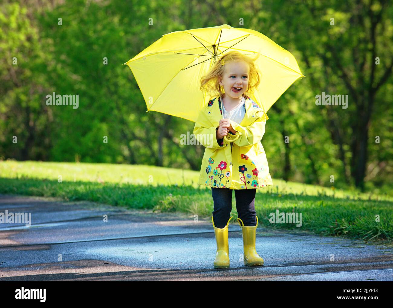Blond toddler girl in yellow raincoat with umbrella Stock Photo Alamy