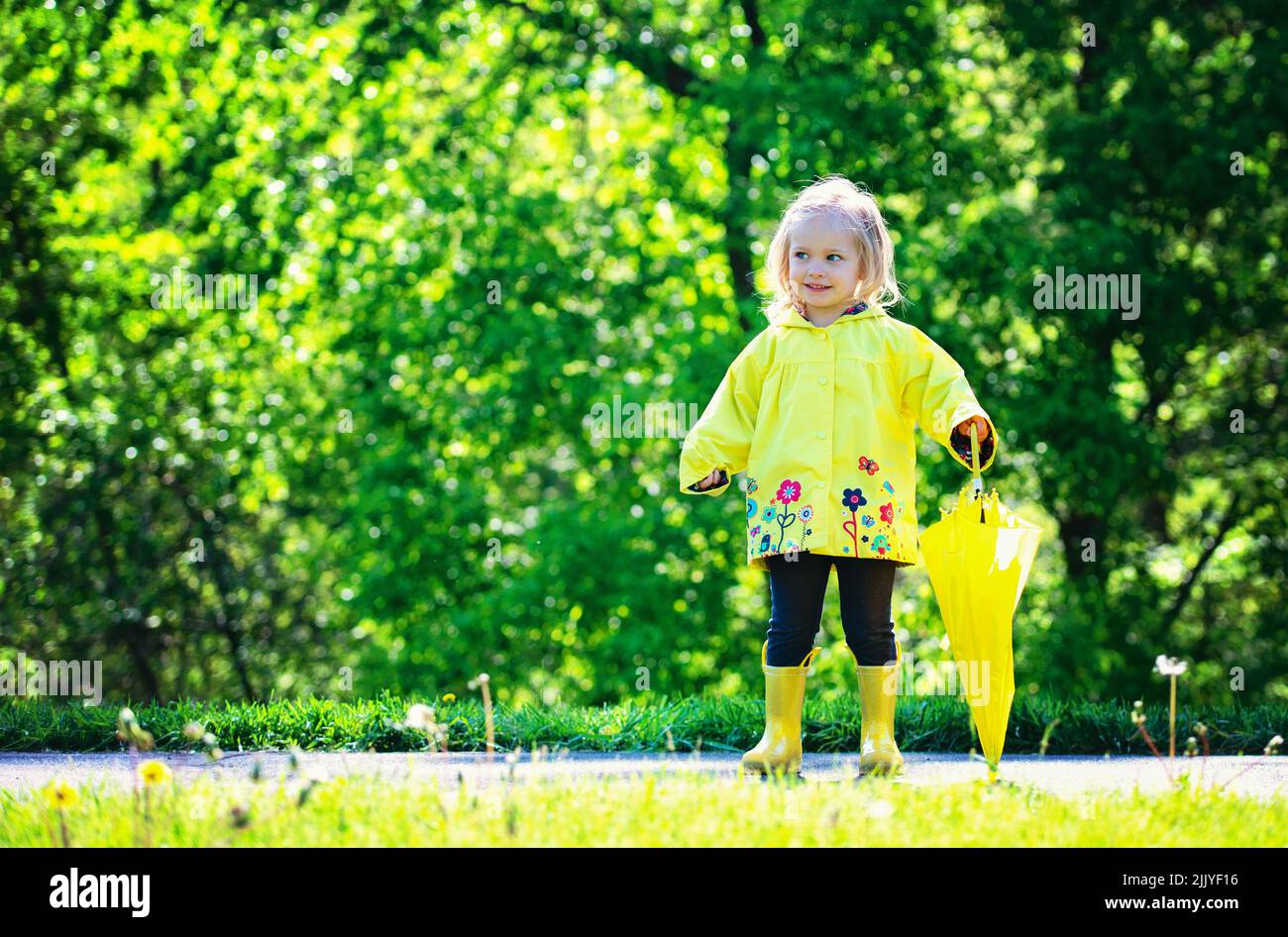 Blond toddler girl in yellow raincoat. Stock Photo