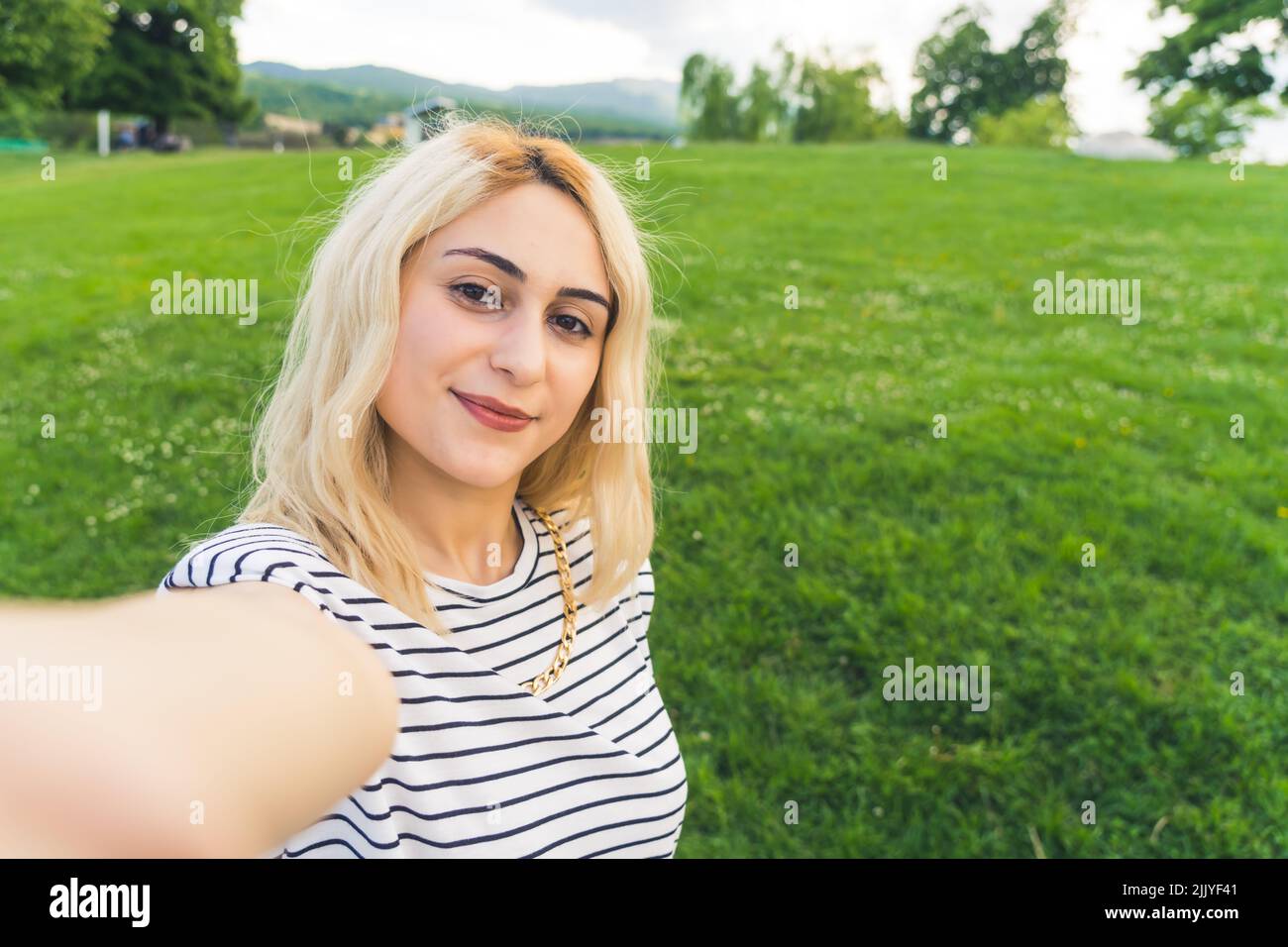 blond cheerful girl making a selfie at the park. outdoor medium closeup . High quality photo Stock Photo