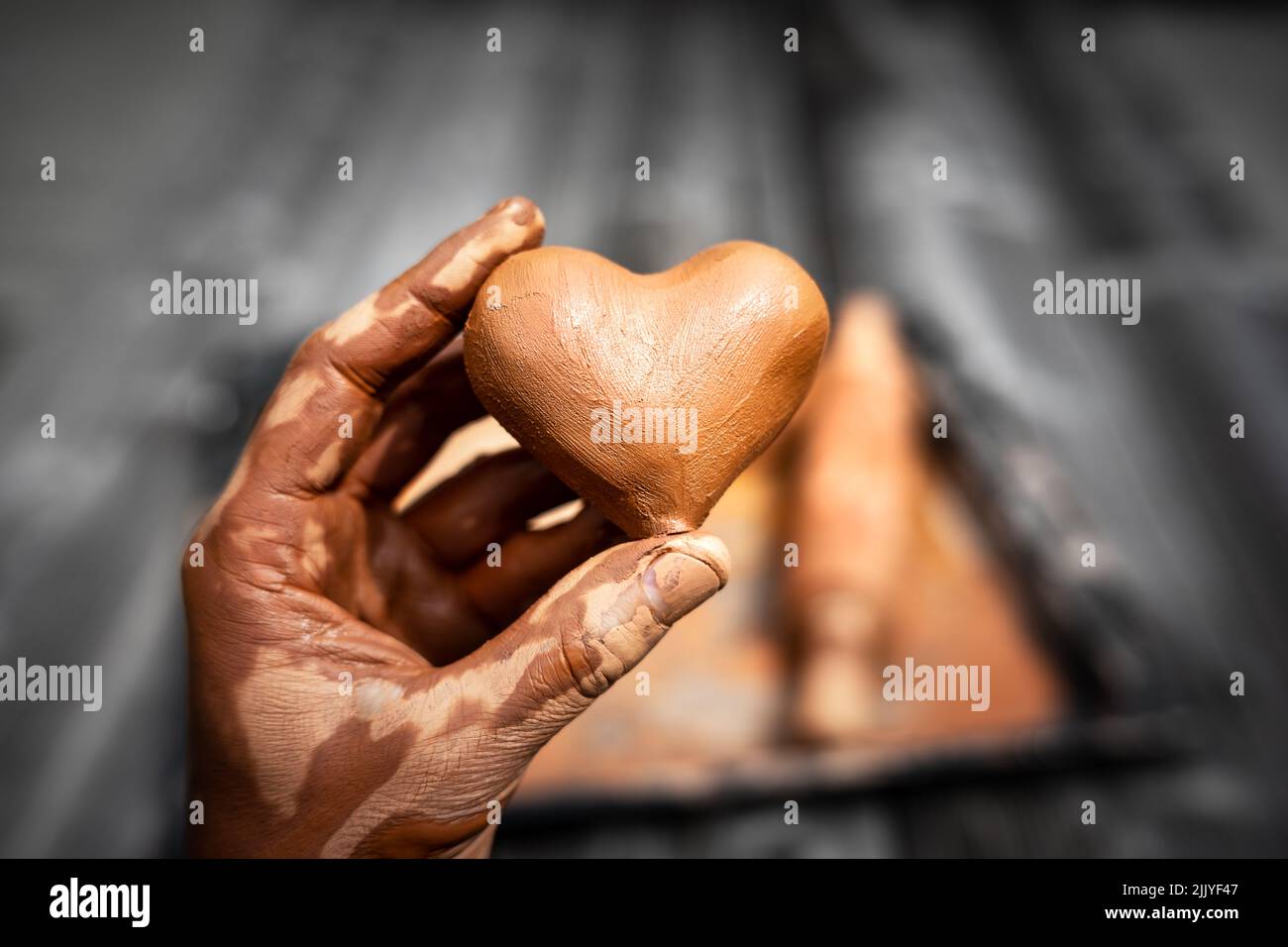 Heart made of potter's clay in the hands of a master potter. Love concept Stock Photo