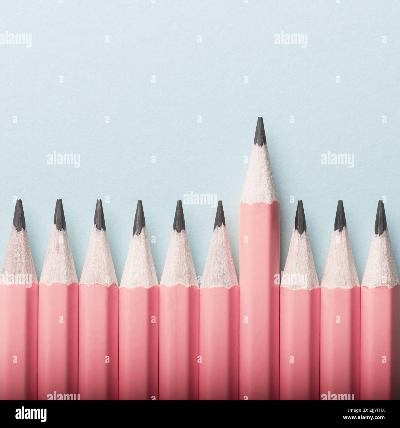 Abstract background of pink pencils lying in a row on blue background. Colour concept Stock Photo